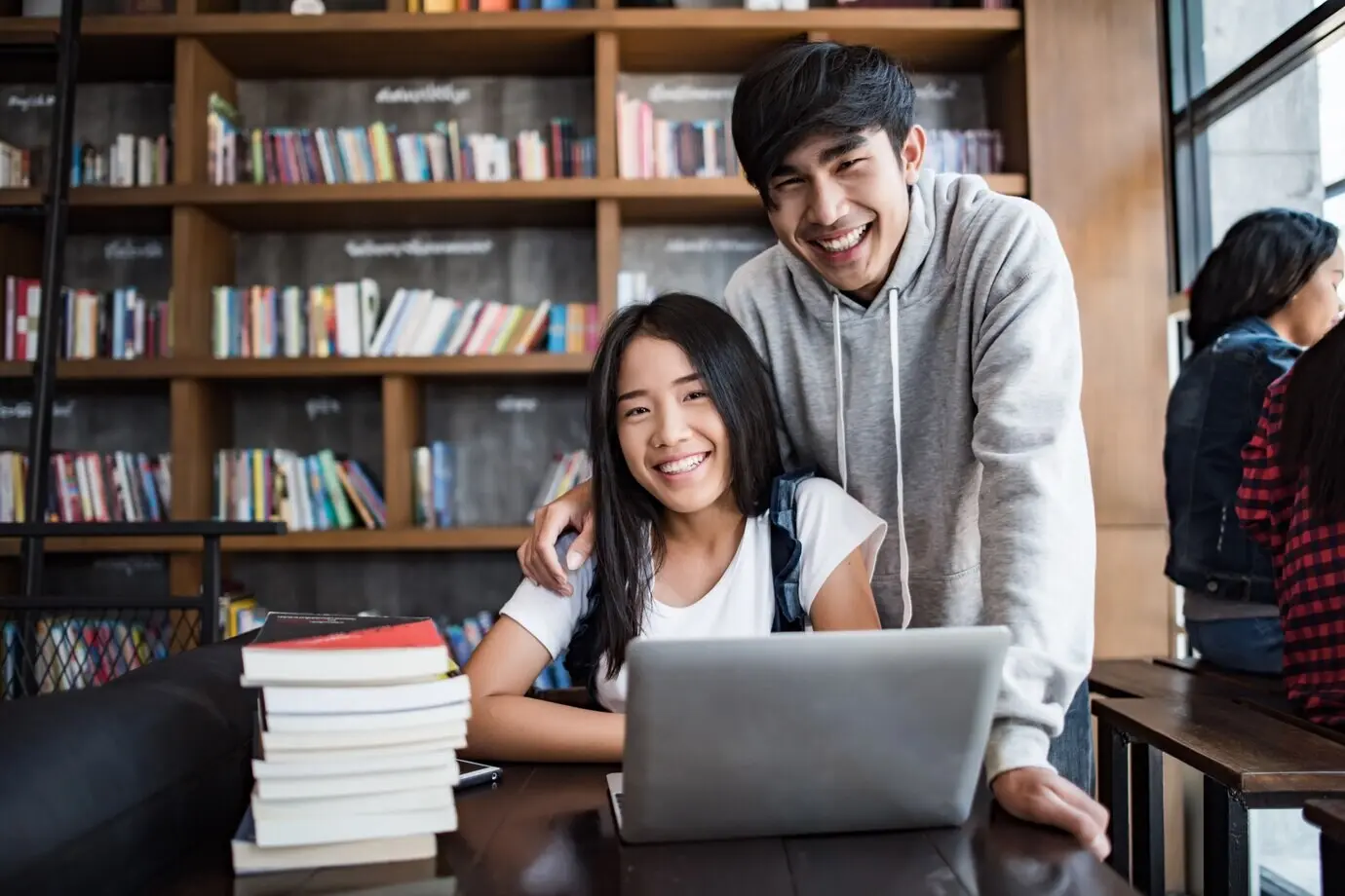 Gruppe fröhlicher befreundeter Studierender, die sich im Café über Wissen unterhalten.