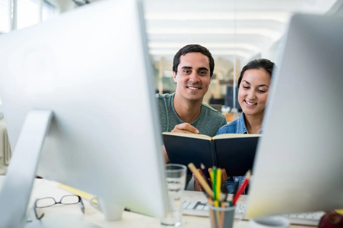 Männliche und weibliche Grafikdesigner interagieren über einem Tagebuch.